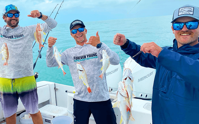 Three anglers display their catch aboard an Islamorada fishing charter.